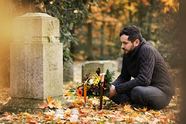Mid adult man with flowers and candles visiting graves
