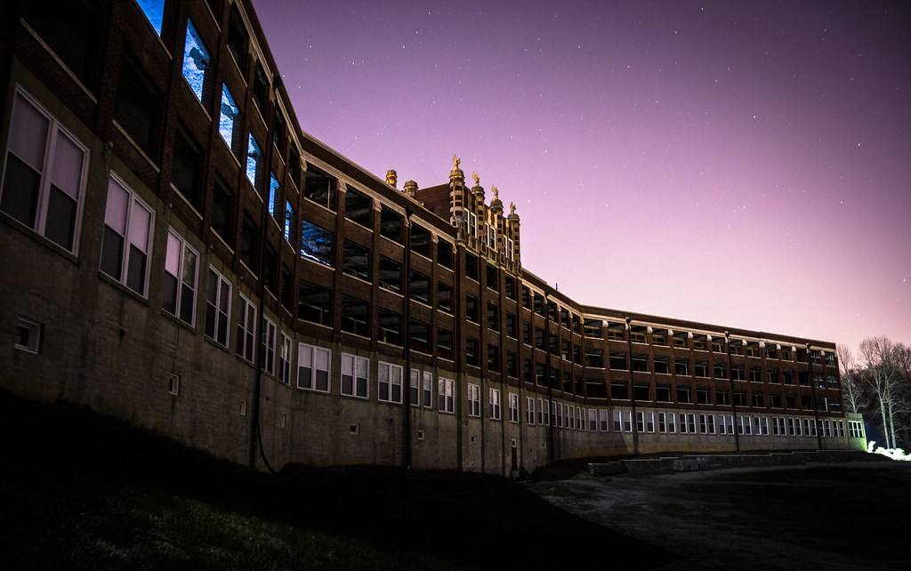 photo shows the outside of the waverly hills sanatorium at nighttime, hulking and foreboding.