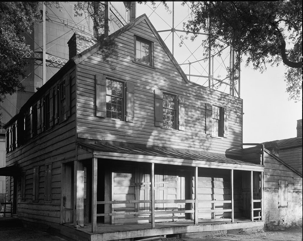 photo shows the exterior of the pirates house in black and white. it's made of weathered wood and brick