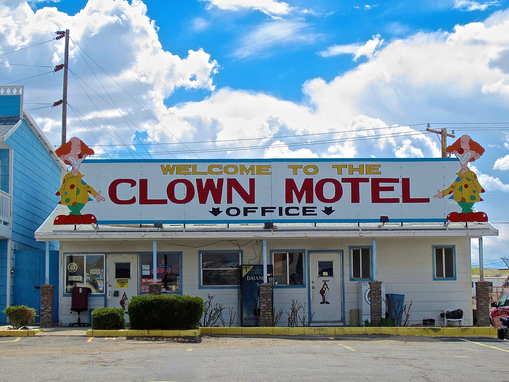 photo shows the office at the clown motel. it has two large circus clowns on the sign and bright colors.