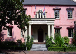 Pink house with columned front porch and hedges