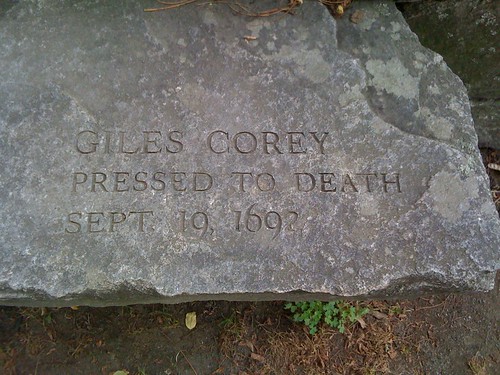 A decrepit tombstone that reads; Giles Corey. Pressed To Death. Sept 19th, 1692