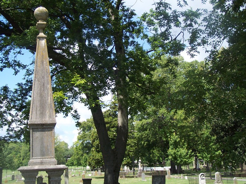 An orb sits atop a pillar shaped tombstone. Smaller tombstones dot the area behind