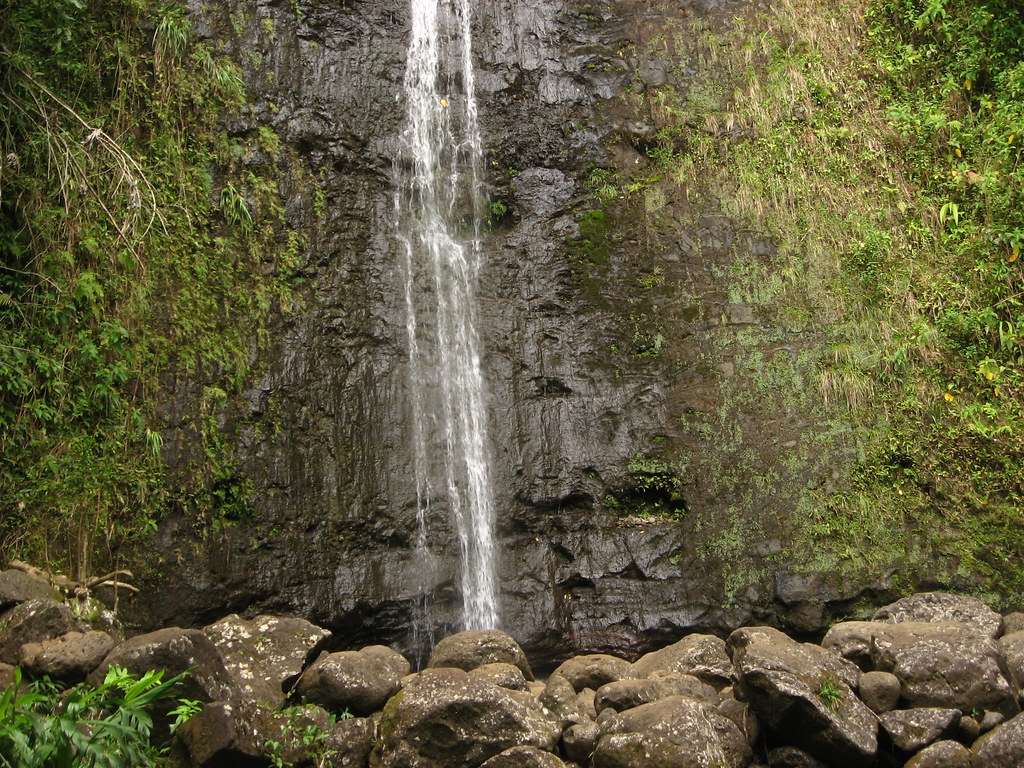 A large waterfall falling between moss covered rocks