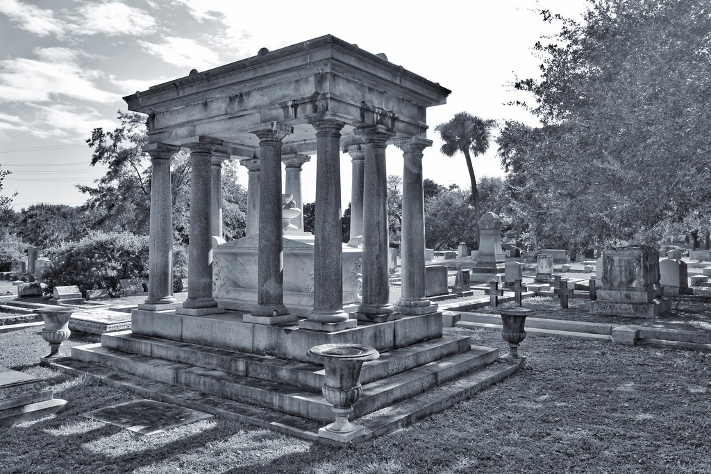 A large greek revival style tomb shaped to look like an ancient temple. Greyscale photo