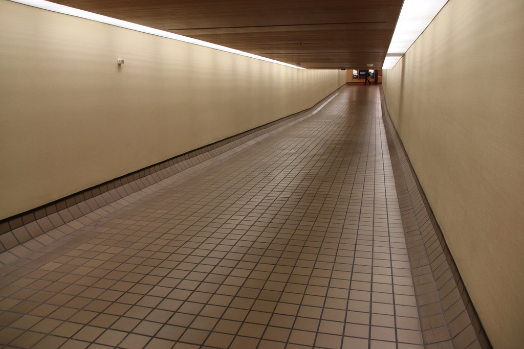 A long tile hallway with white walls stretching into the distance