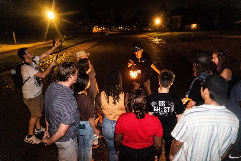 Group of guests stand before a tour guide carrying a lit lantern during a tour with Crabtown Ghost Tour | Annapolis, MD | US Ghost Adventures