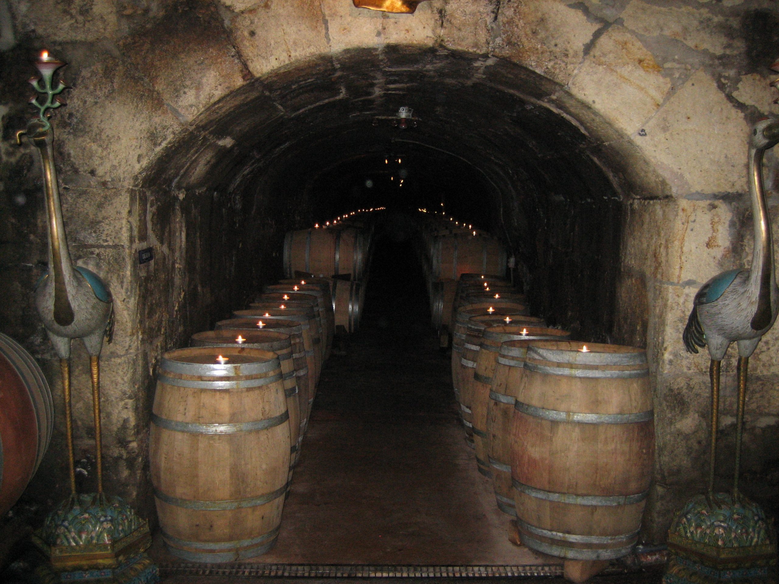 a number of stacked barrels in an underground brick tunnel