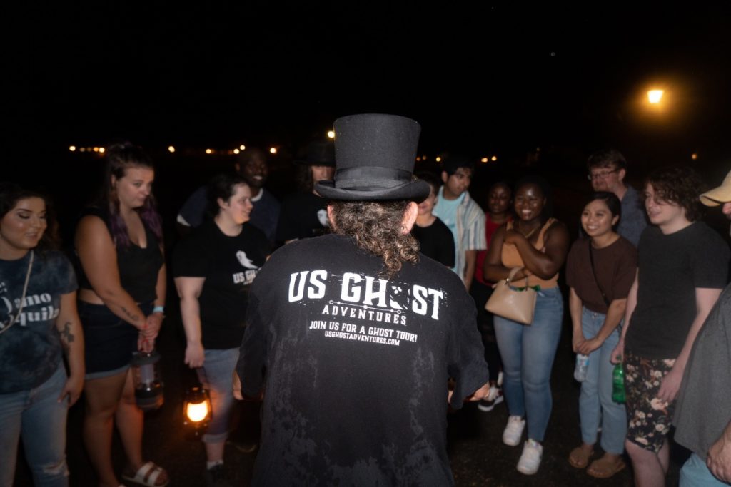 A group of people listening closely as a tour guide tells them ghost stories on a ghost tour