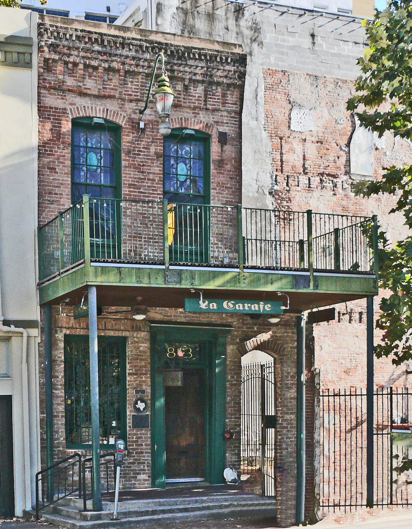 Houston. A narrow brick building with a green metal balcony reaching out from it